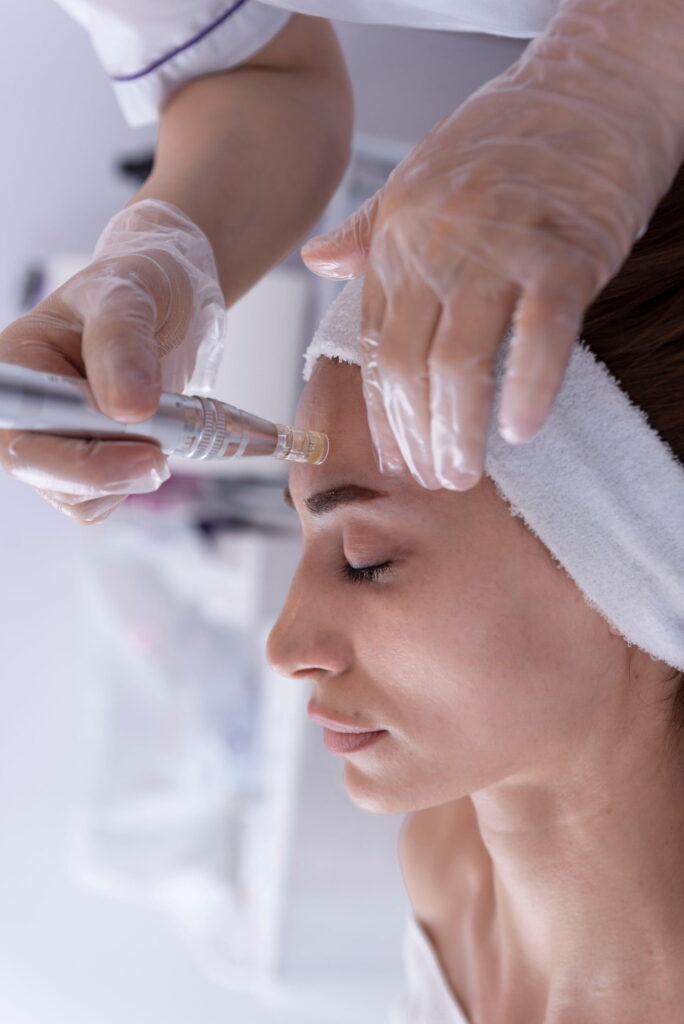 close up of Cosmetologist,beautician applying facial dermapen treatment on face of young woman customer in beauty salon.Cosmetology and professional skin care, face rejuvenation.